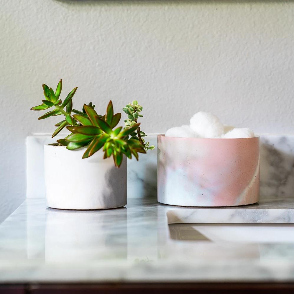 4 inch and 5 inch concrete vessels holding bathroom items on counter.