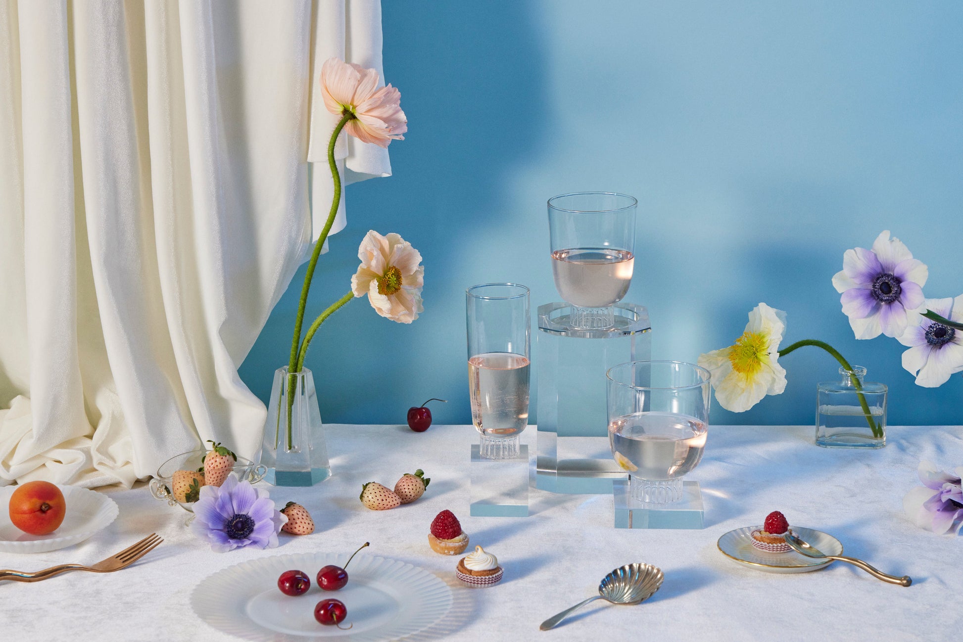 Sprezz clear stemless champagne flute and stemless wine cups filled with rose on a table with flowes and dessert