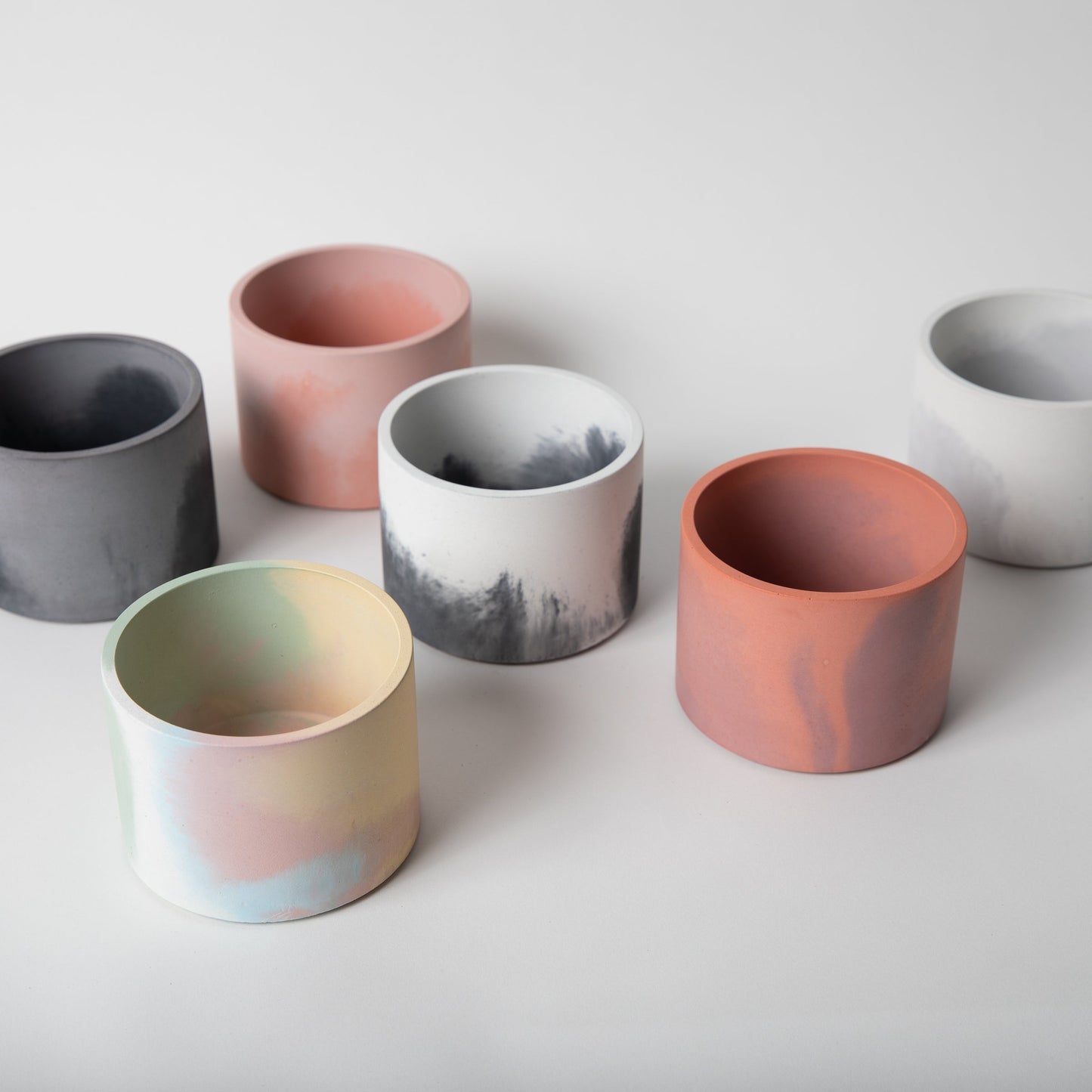 Variety of 4 inch concrete vessels in different colors.