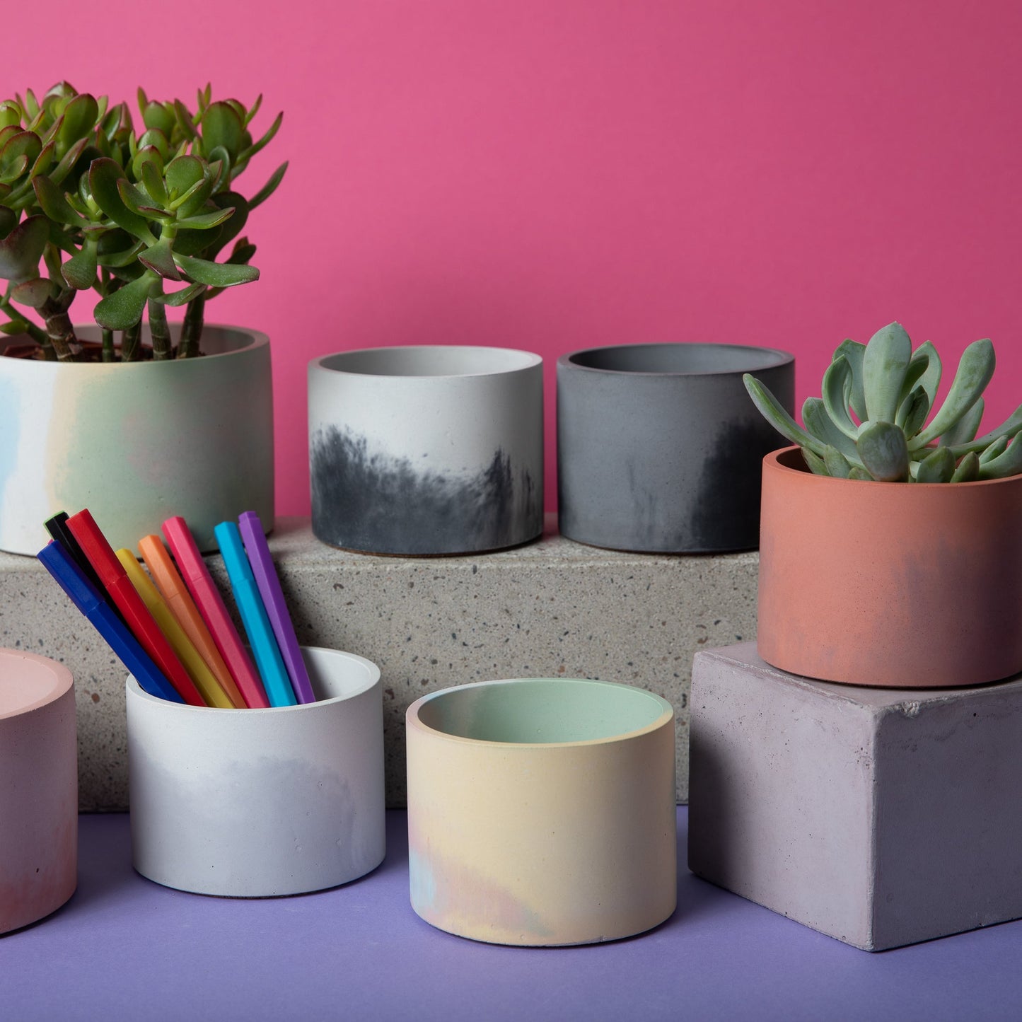 5 inch concrete vessel next to 4 inch vessels with plants and pens for scale.