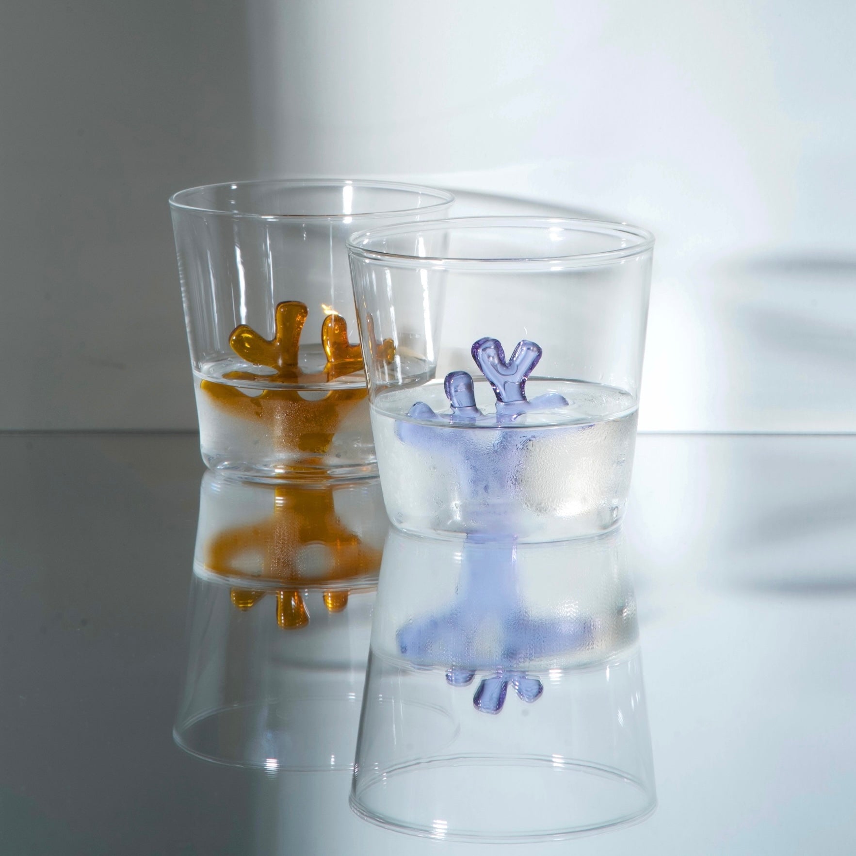 two Sprezz whimsical colored glass drinkware serving cold water. Tumblers are made of borosilicate glass thats dishwasher safe