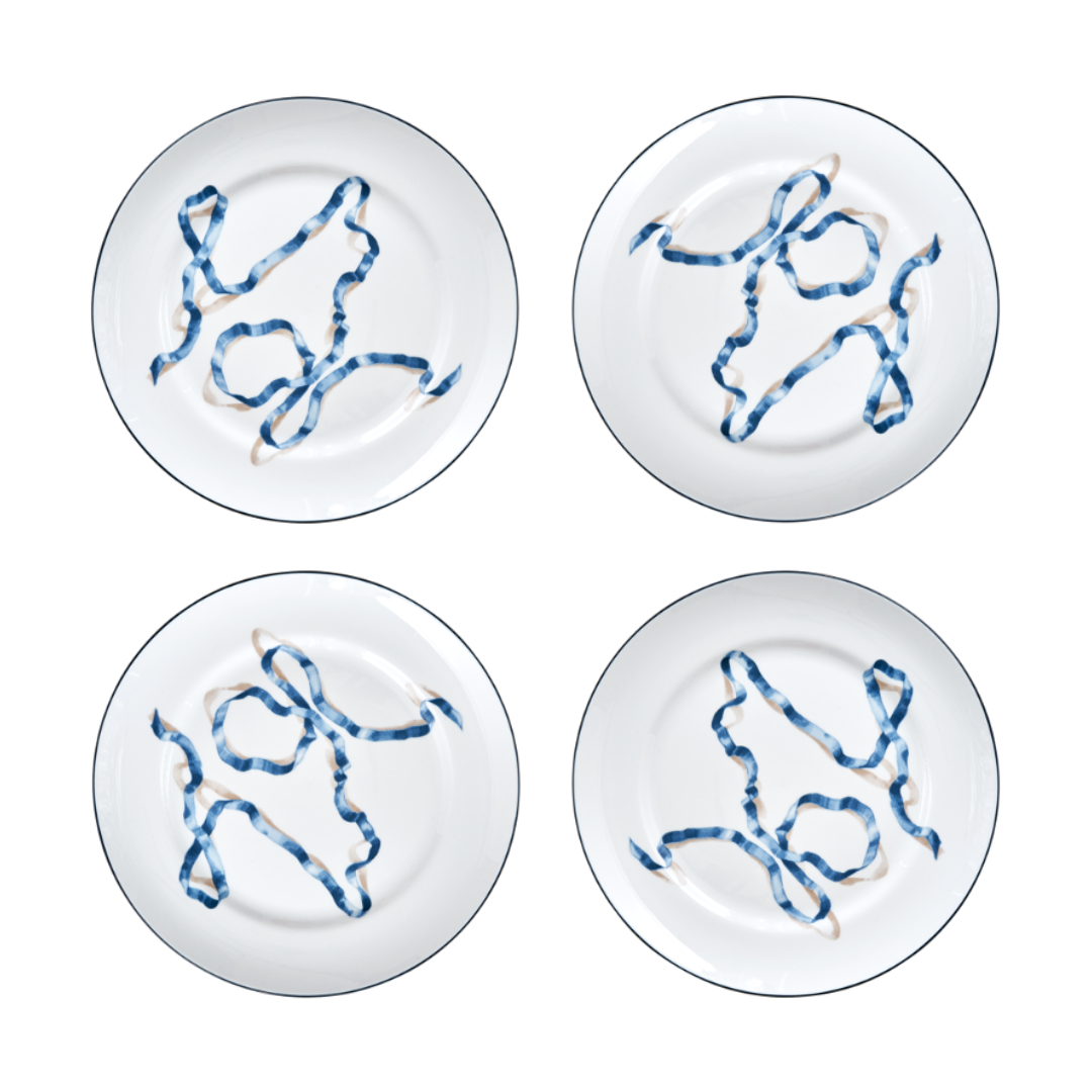 A set of four ribbon dinner plates in Blue. Comprised of a series of ribbon adorned plates, the collection is a delightful departure from traditional holiday decor. The plates are inspired by prints of citrus fruits from the 17th and early 18th centuries showing ribbons bearing the names of the depicted fruit.